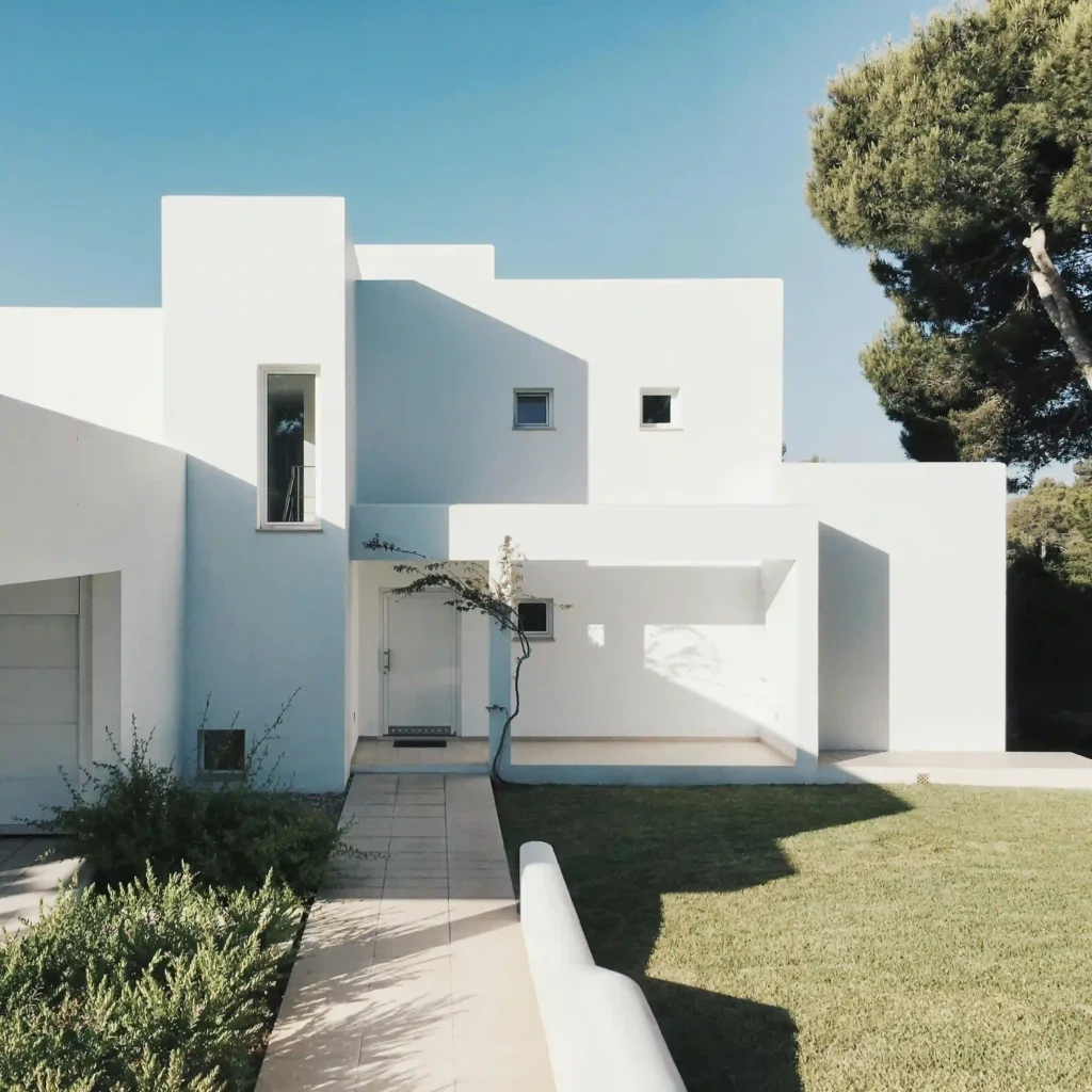 Modern house with a clean white exterior and a well-maintained green lawn in front, designed and built by Manhattan Contracting, general contractors in NYC